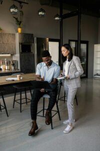 This is an image of a man and a woman looking at a laptop in an office.