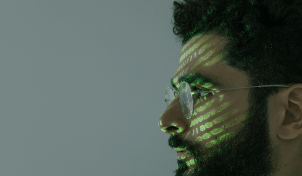 This is an image of a man's face with code being reflected on it.