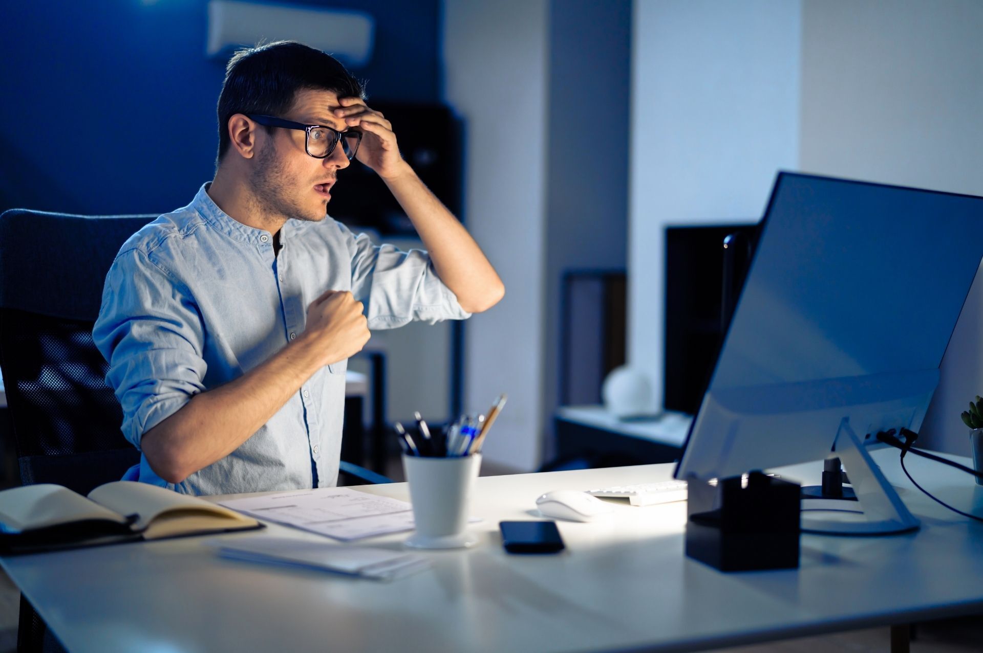 This is an image of a stressed-looking man looking at a laptop screen.